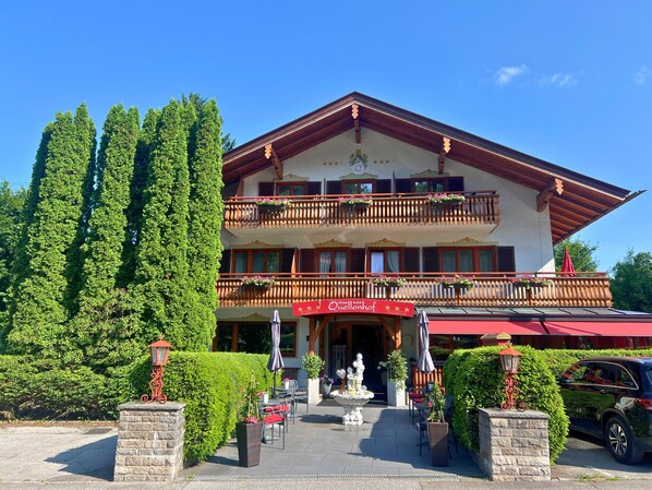 A hotel with a red awning, outdoor seating, and a fountain.