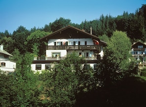 A multi-story building with balconies, surrounded by trees.