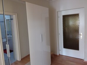 Une pièce dotée d’une porte coulissante, d’un petit tabouret et d’une salle de bain visible, équipée d’un lavabo et d’un miroir.