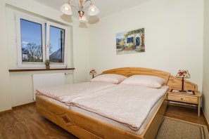 Een slaapkamer met een houten bed, twee nachtkastjes, een raam met uitzicht en een schilderij aan de muur.
