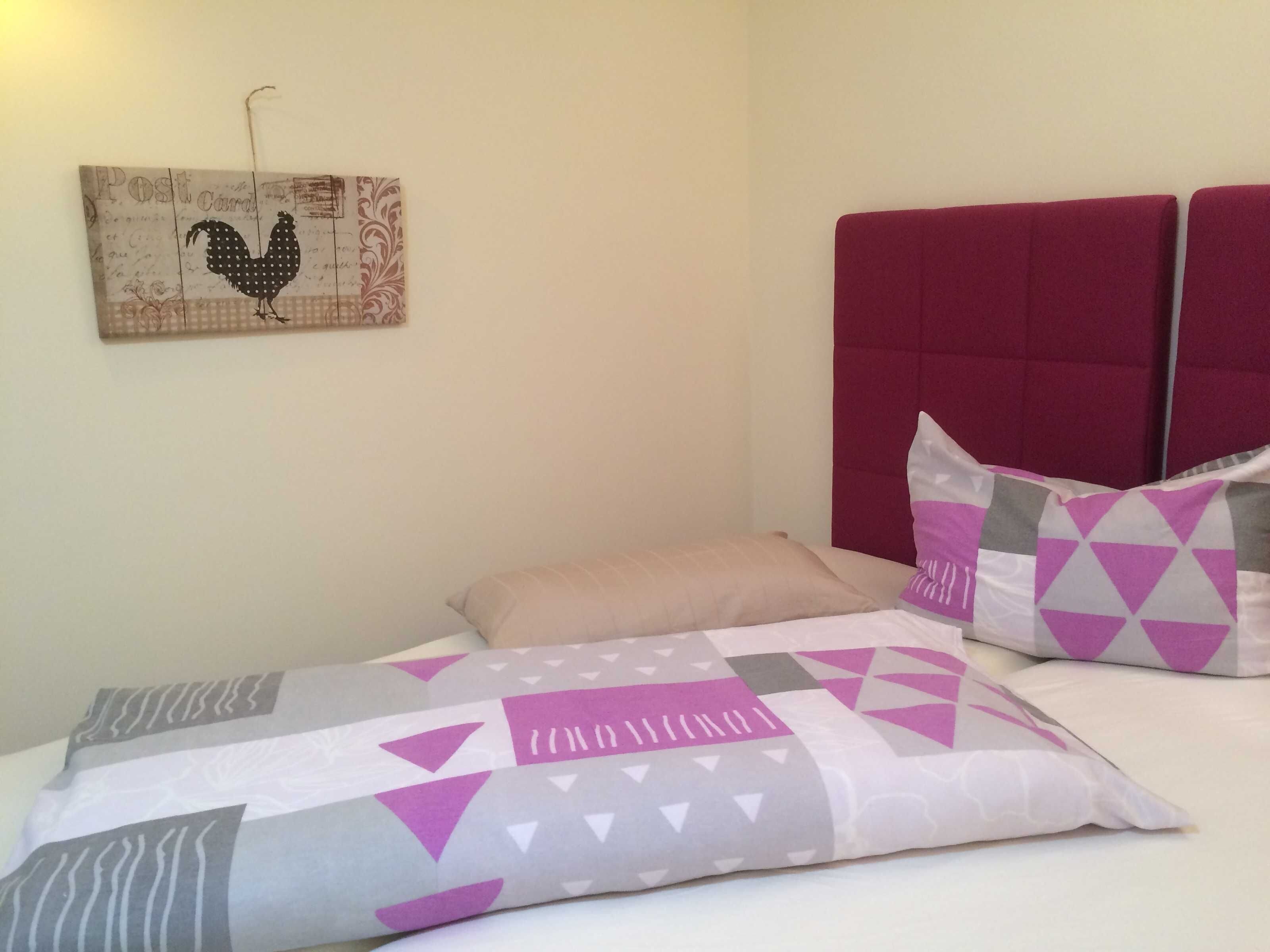 A bedroom with a bed, pillows, a headboard, and a wall decoration.