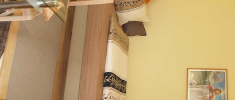 Ein Bett mit hölzernem Kopfteil, einem gemusterten Kissen und einem gerahmten Bild an der Wand.