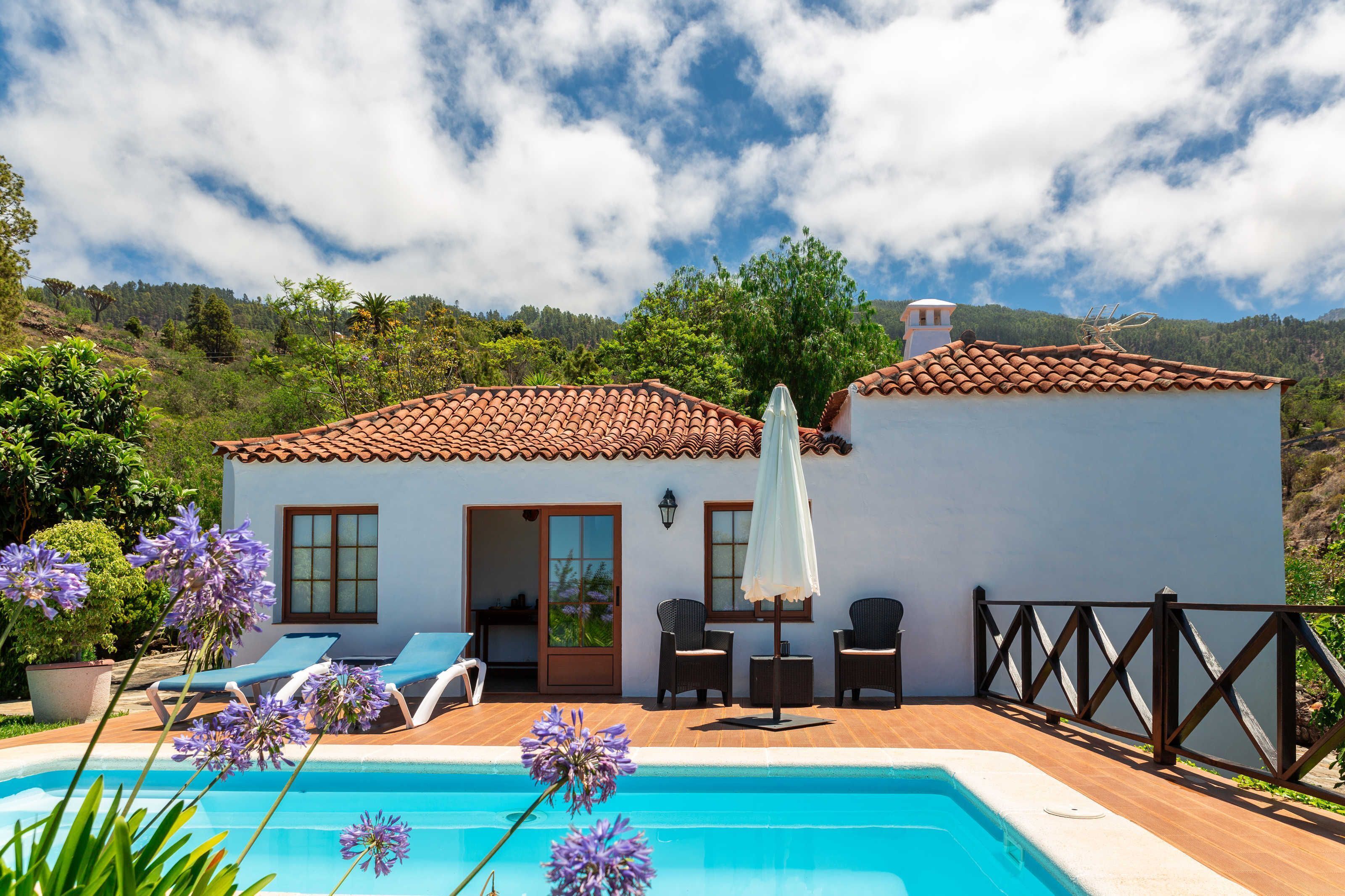 Eine Villa mit Swimmingpool, Sitzgelegenheiten im Freien und Blick auf die Hügel.