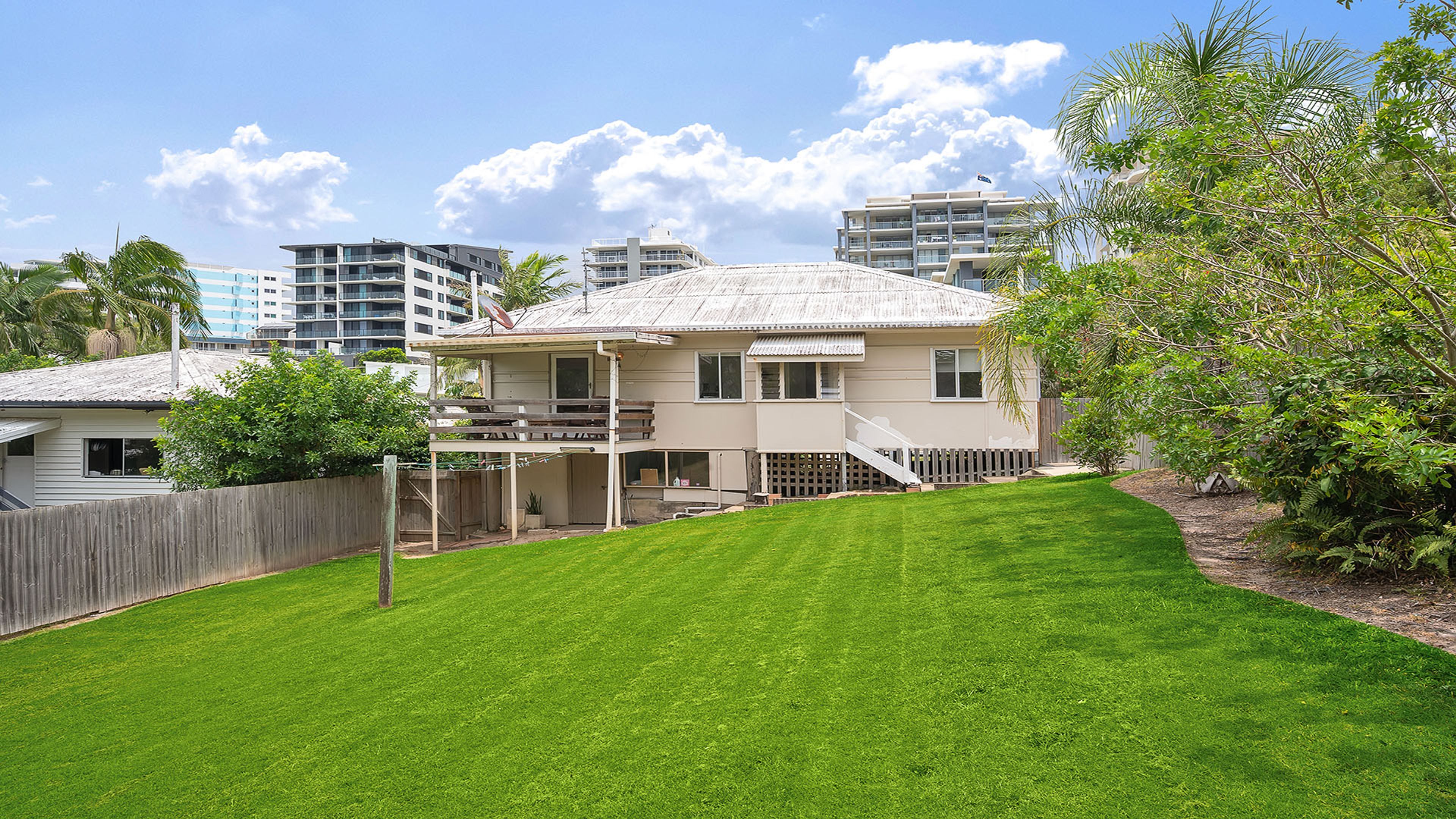 A two-story house with a covered patio and a fenced backyard.