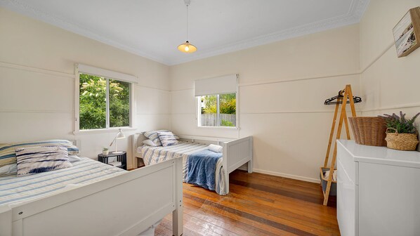 A bedroom with two beds, a window, a desk, and a dresser.