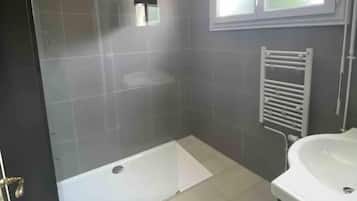 A bathroom with a glass-enclosed shower, a white sink, and a towel rack.