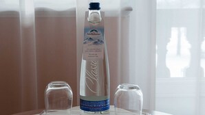 A bottle of Adelsolzer mineral water on a tray with two glasses. - Double Room South - Gästehaus Florian (Tegernsee)