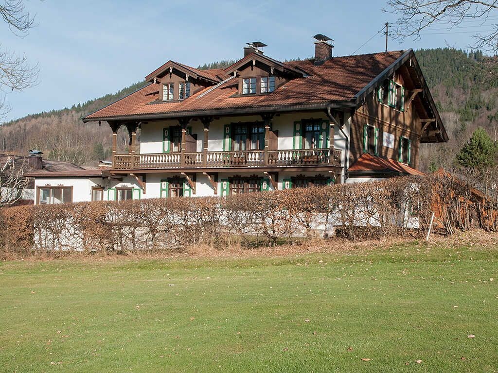 A traditional chalet with a balcony, a wooden facade, and a sloped roof.