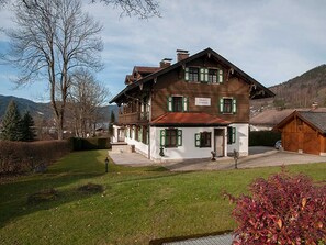 Ein traditionelles Holzhaus mit geneigtem Dach, einer Veranda und einem Schild, das es als Pension kennzeichnet.