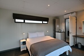A modern hotel room with a large bed, bedside tables, a desk, and a wardrobe.