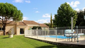 Una casa con piscina, patio cercado y césped bien cuidado.