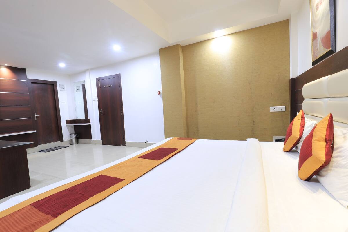 A hotel room with a large bed, wooden wardrobe, and a small bathroom.