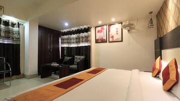 A hotel room with a large bed, a desk, a chair, a wardrobe, and a curtain.