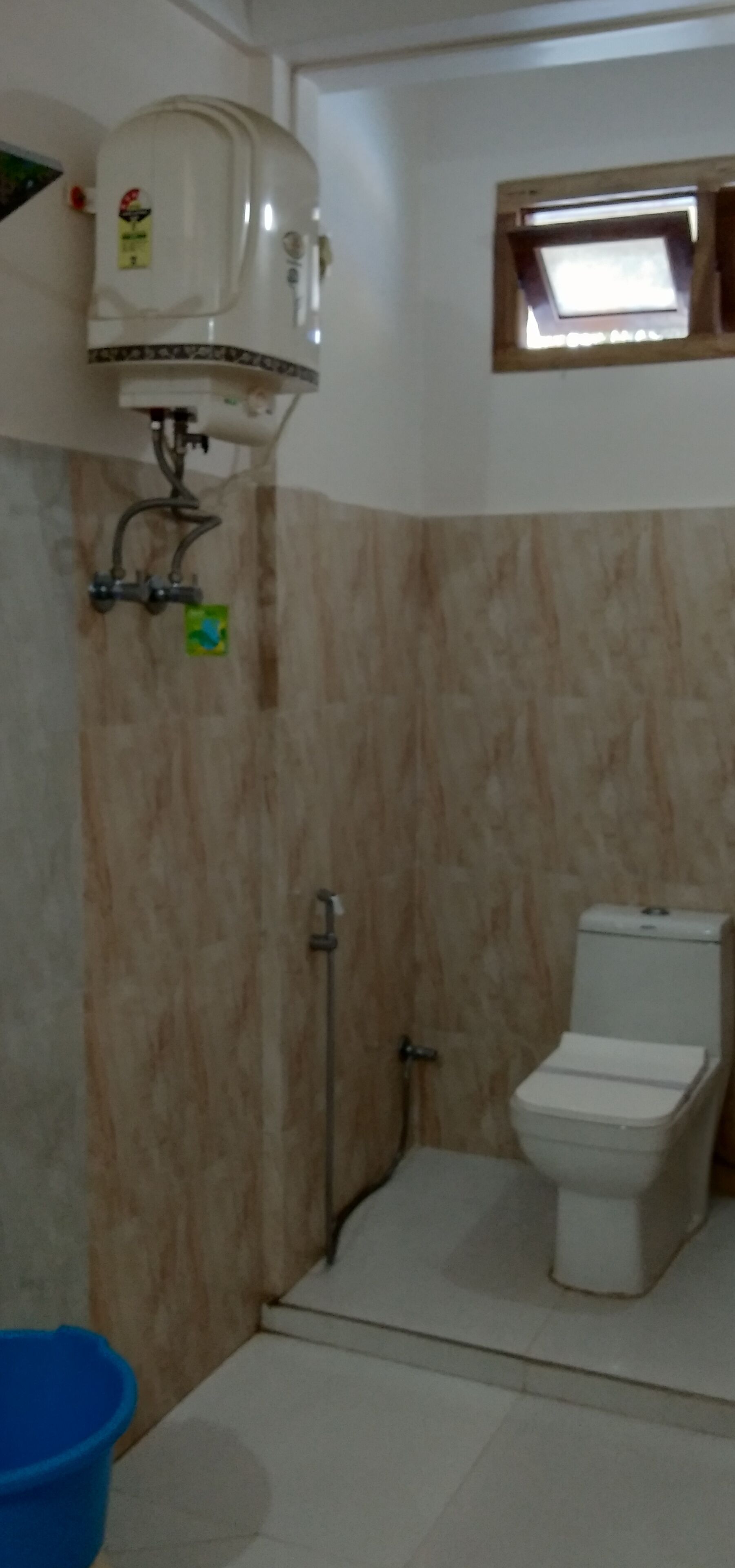 Een badkamer met toilet, douche en raam.