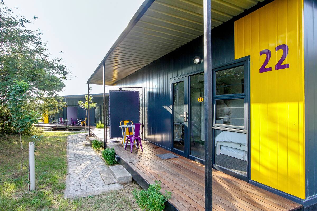 Un edificio moderno con terraza de madera y una pared amarilla brillante con el número 22.