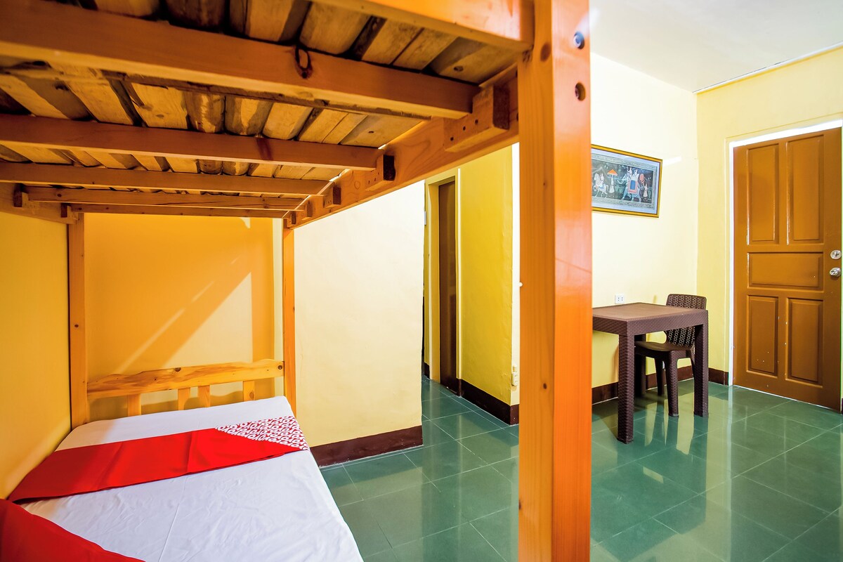 A room with a bunk bed, a dining table, and a door.