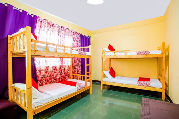 Une chambre avec deux lits superposés, des rideaux violets et un sol vert.