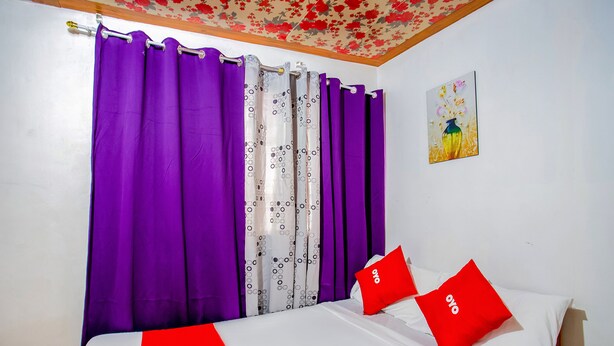 A bedroom with a bed, purple curtains, and a painting on the wall. - Mye Tourist Inn (Parañaque)