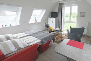 Una camera da letto con un letto, due sedie, un tavolo, una TV e una finestra.