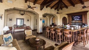 A spacious lobby with a bar area, wooden furniture, and a high ceiling with exposed beams.