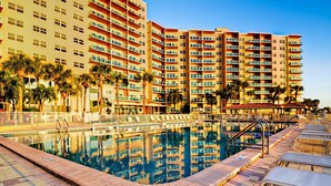 A hotel with a swimming pool, multiple balconies, and palm trees. - Regatta Beach Club C1009 '90 day min stay with 2 week lead time' (Clearwater Beach)