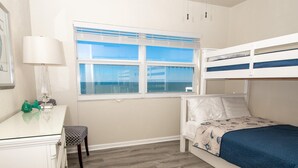 A bedroom with a bunk bed, a desk with a lamp, and a window with blinds. - Regatta Beach Club C1009 '90 day min stay with 2 week lead time' (Clearwater Beach)