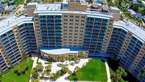 A large hotel with multiple floors, a central courtyard with a swimming pool, and surrounding greenery. - Regatta Beach Club C1009 '90 day min stay with 2 week lead time' (Clearwater Beach)