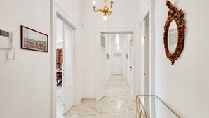 A hallway with a chandelier, a framed picture, a mirror, and a phone on the wall. - GuestHost - Elegant and roomy apartment equipped with every comfort to accommodate up to 6 people, with 3 bedrooms and 2 bathrooms. The location is enviable: in front of the lively promenade of Bari, the beating heart of the city with its events, a 2-min (Bari)
