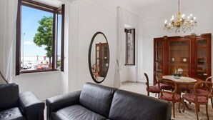 A room with a leather sofa, a dining table with chairs, a chandelier, and a large mirror. - GuestHost - Elegant and roomy apartment equipped with every comfort to accommodate up to 6 people, with 3 bedrooms and 2 bathrooms. The location is enviable: in front of the lively promenade of Bari, the beating heart of the city with its events, a 2-min (Bari)