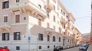 A multi-story building with balconies, a parking sign, and parked cars. - GuestHost - Elegant and roomy apartment equipped with every comfort to accommodate up to 6 people, with 3 bedrooms and 2 bathrooms. The location is enviable: in front of the lively promenade of Bari, the beating heart of the city with its events, a 2-min (Bari)
