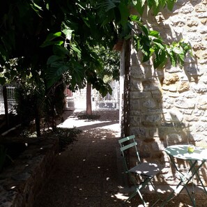 Un mur de pierre, un sentier étroit et une chaise en métal.