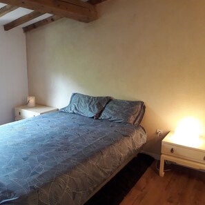 Une chambre à coucher avec un lit, une table de chevet et une lampe fixée au mur.
