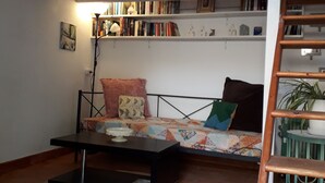 A cozy reading nook with a sofa, a coffee table, and a bookshelf filled with books. - Charmante maisonnette rénovée proche Uzès Charming little house near Uzès (Foissac)