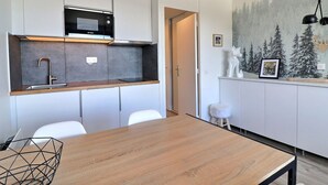 A modern kitchen with white cabinets, a built-in microwave, and a wooden dining table.
