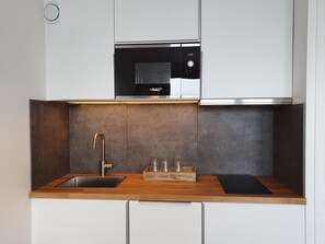 A compact kitchen with a stainless steel sink, a Bosch microwave, and a wooden countertop.