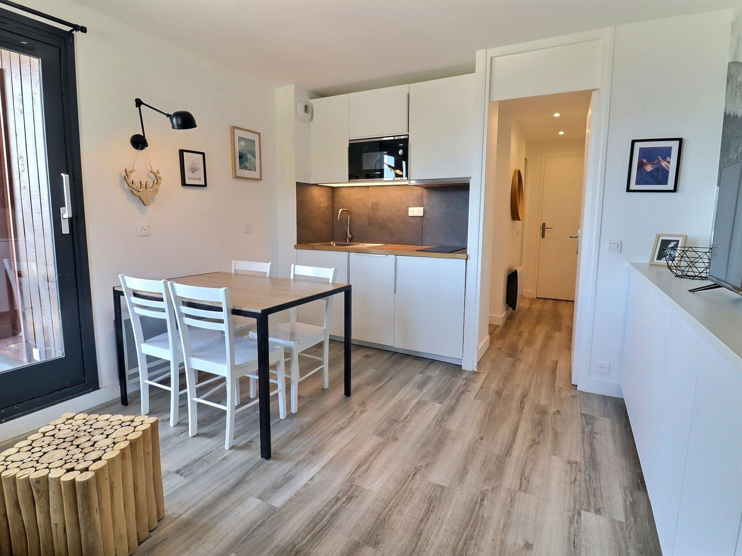 A modern kitchen with white cabinets, a wooden dining table, and chairs.