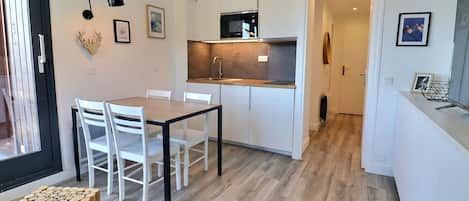Una cocina moderna con armarios blancos, una mesa de comedor de madera y sillas.