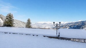 Paisagem coberta de neve com uma cerca de metal e um lampião.