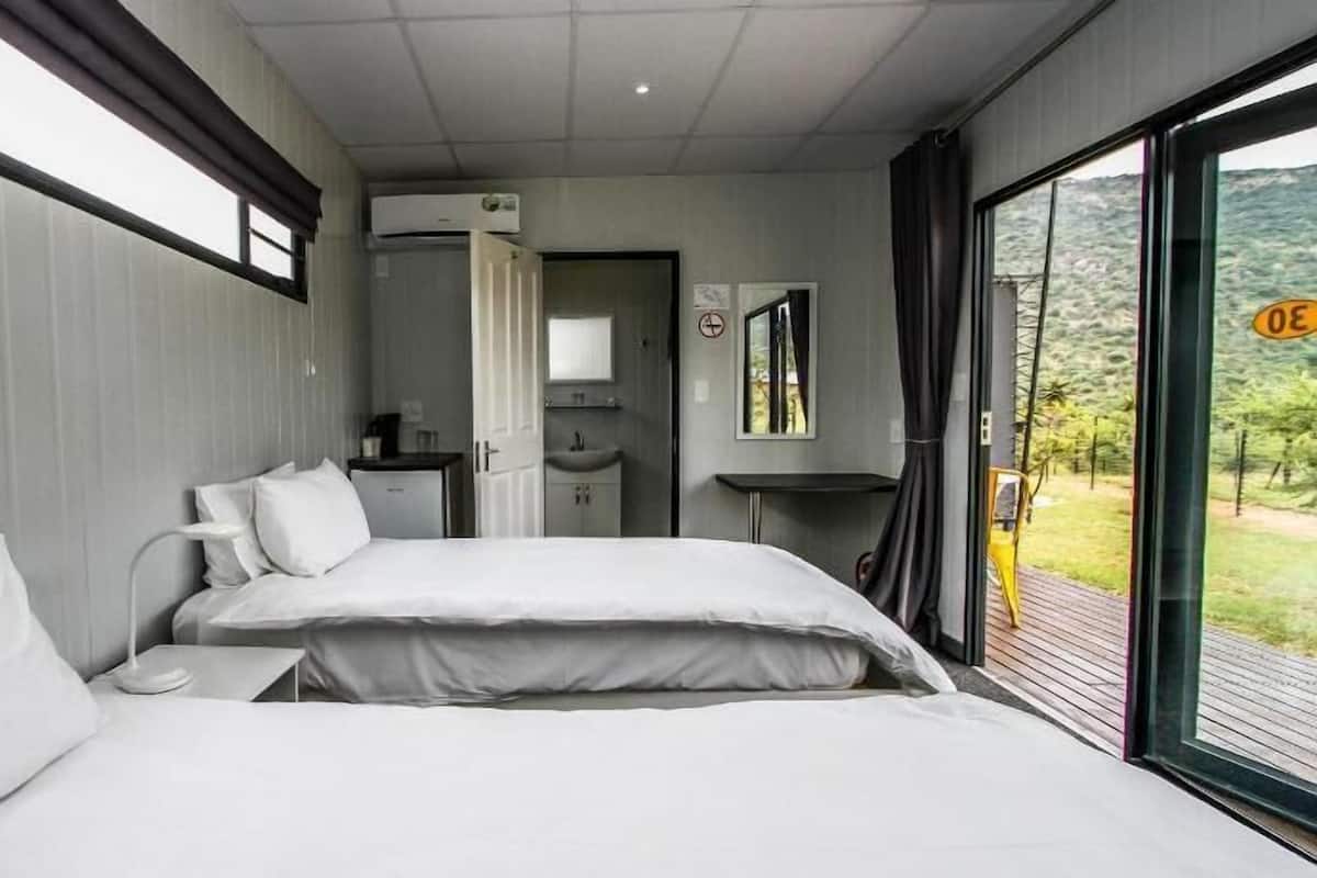 Un dormitorio moderno con una cama grande, una mesita de noche, un espejo y vistas al exterior.