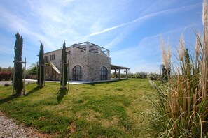 Un edificio de piedra con techo de cristal, rodeado de hierba y plantas altas.