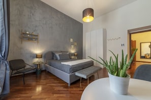 Une chambre à coucher moderne avec un lit, des tables de chevet, un banc, une plante en pot et une armoire.