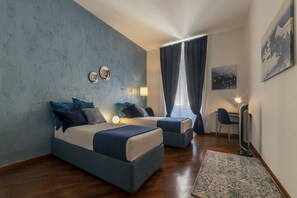 A modern bedroom with two beds, a desk, and a chair.