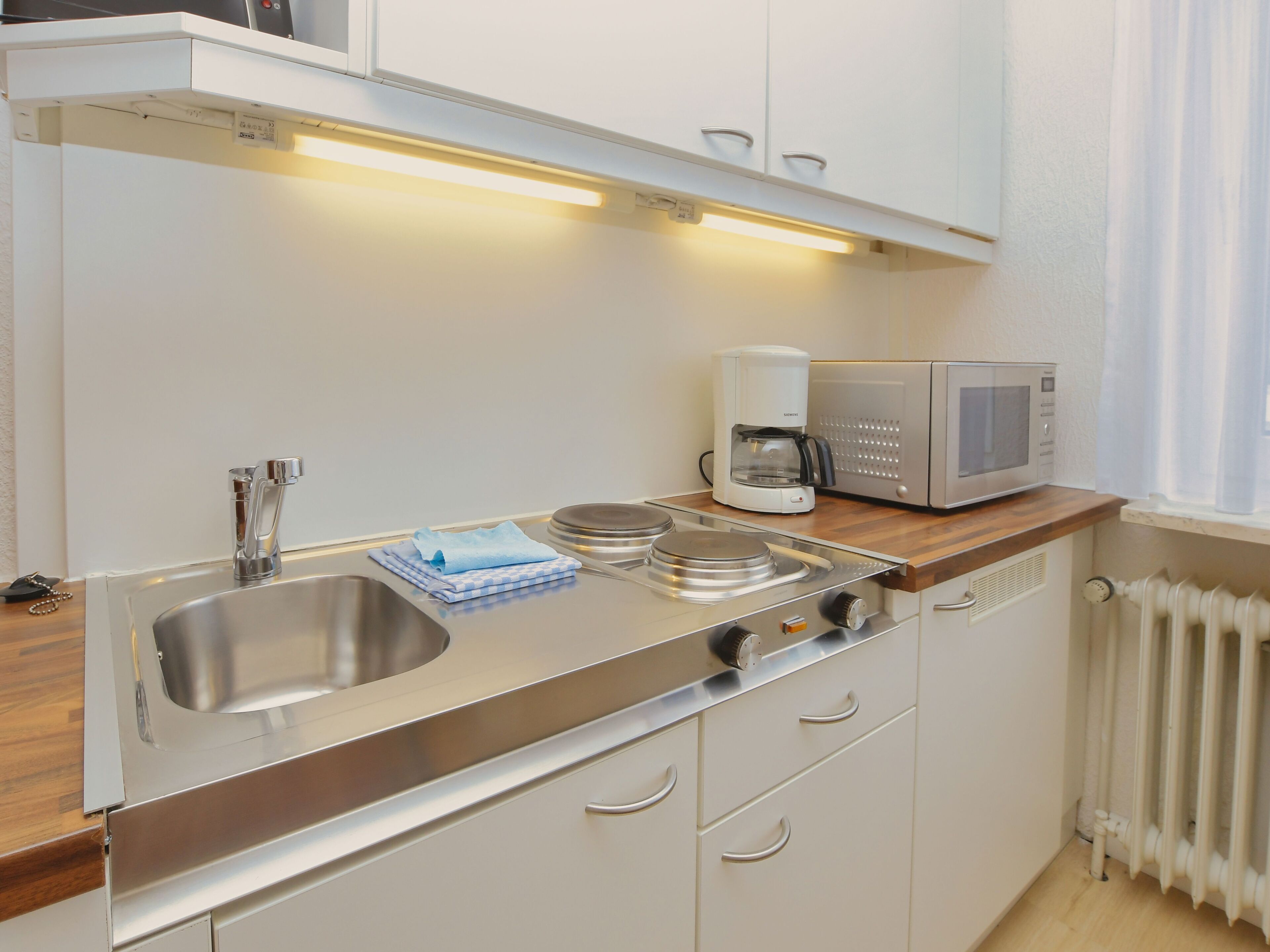 A modern kitchen with stainless steel appliances, a sink, and wooden countertops.