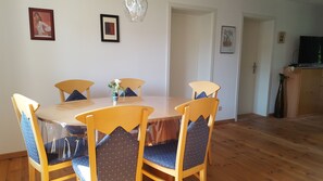 A dining area with a round table, four chairs, and a vase with flowers.