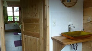 Interior de madera con baño que incluye un tocador de madera y un lavamanos de vidrio.