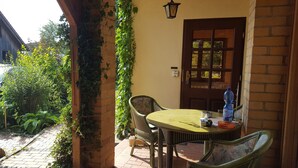 An outdoor patio with a round table, chairs, a water bottle, and a door with a window.