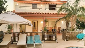 A two-story building with a patio area featuring lounge chairs, a small pool, and a dining area with tables and chairs. - 6 bedroom beautiful home in La Azohia (La Azohia)