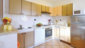 A kitchen with white cabinets, a stainless steel refrigerator, a dishwasher, and a microwave. - Stunning home in Rabac (Rabac)