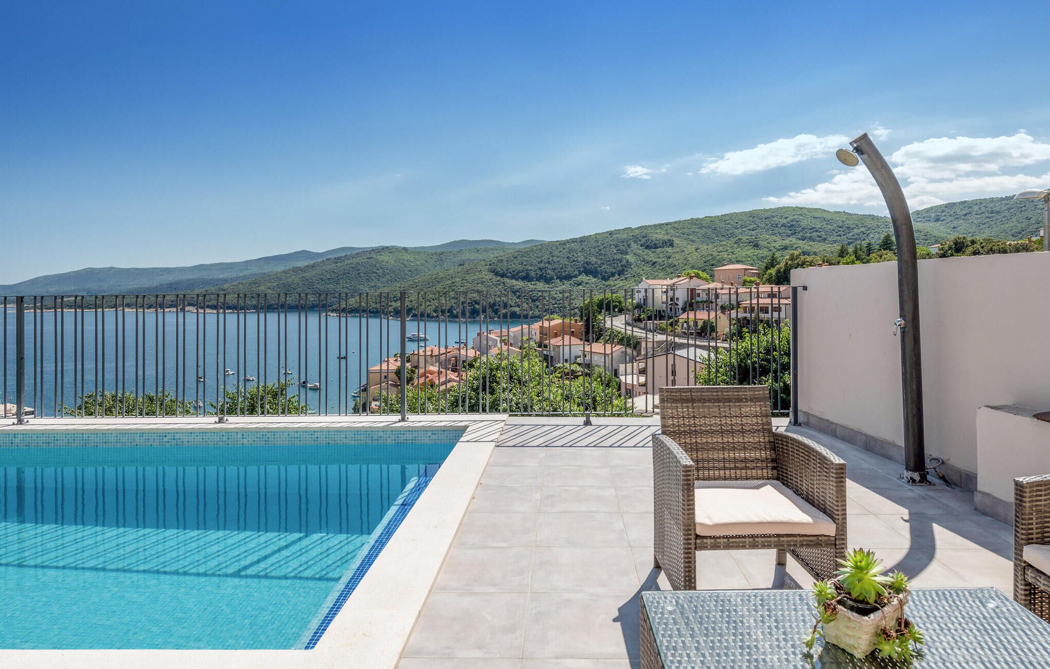 Piscina con vistas a un pueblo costero y montañas.