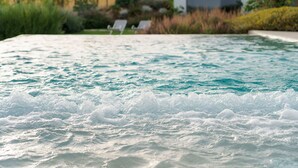Ein Whirlpool mit Blick auf einen angelegten Garten und ein Gebäude im Hintergrund.